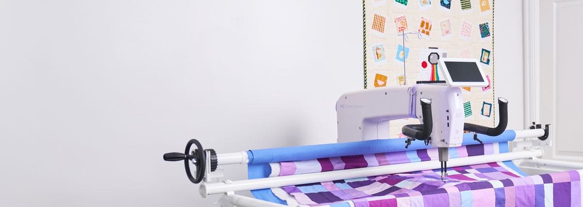 The HQ Super Sixteen on the HQ Little Foot Frame with a purple pieced quilt loaded